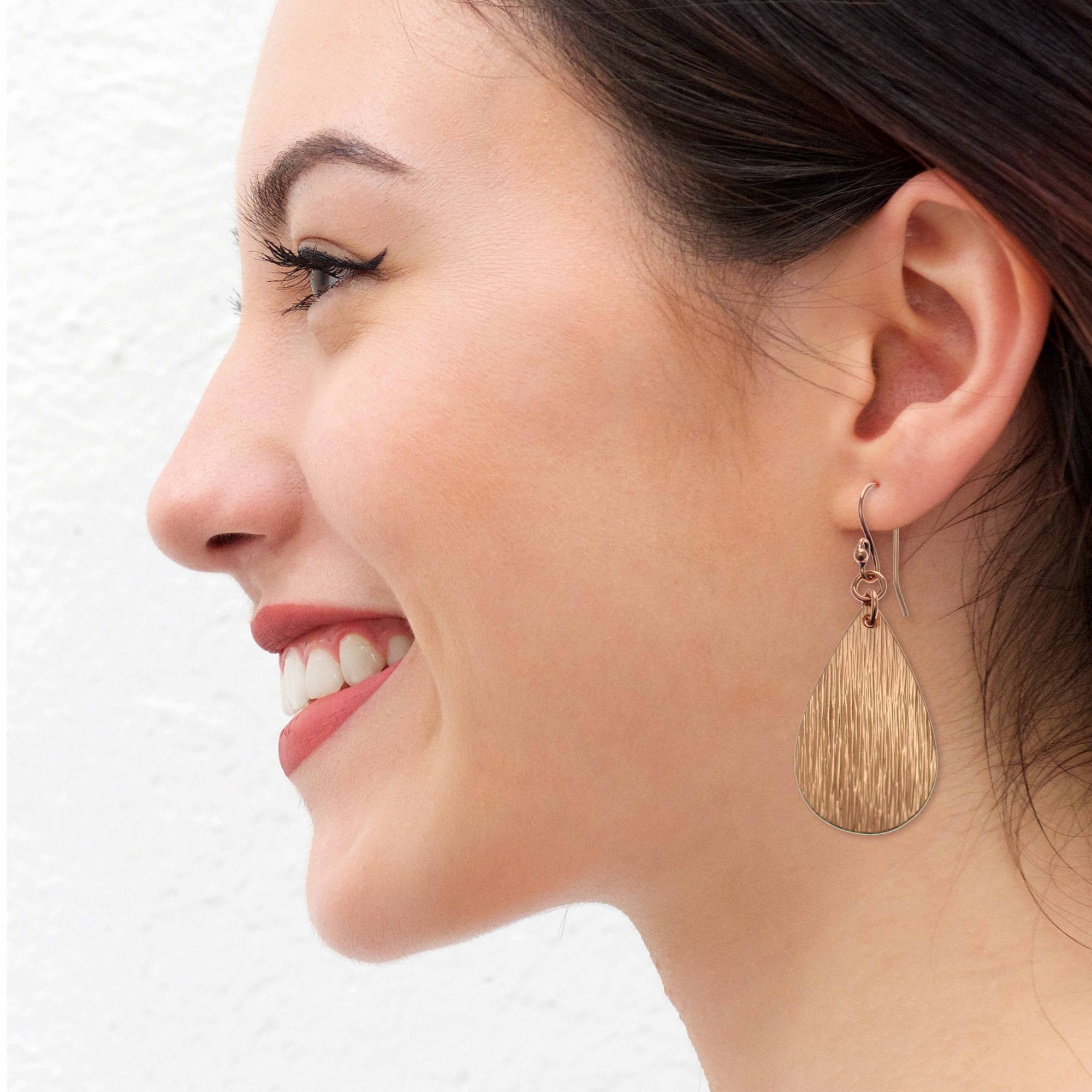 Smiling Woman Wearing Bark Embossed Small Teardrop Earrings