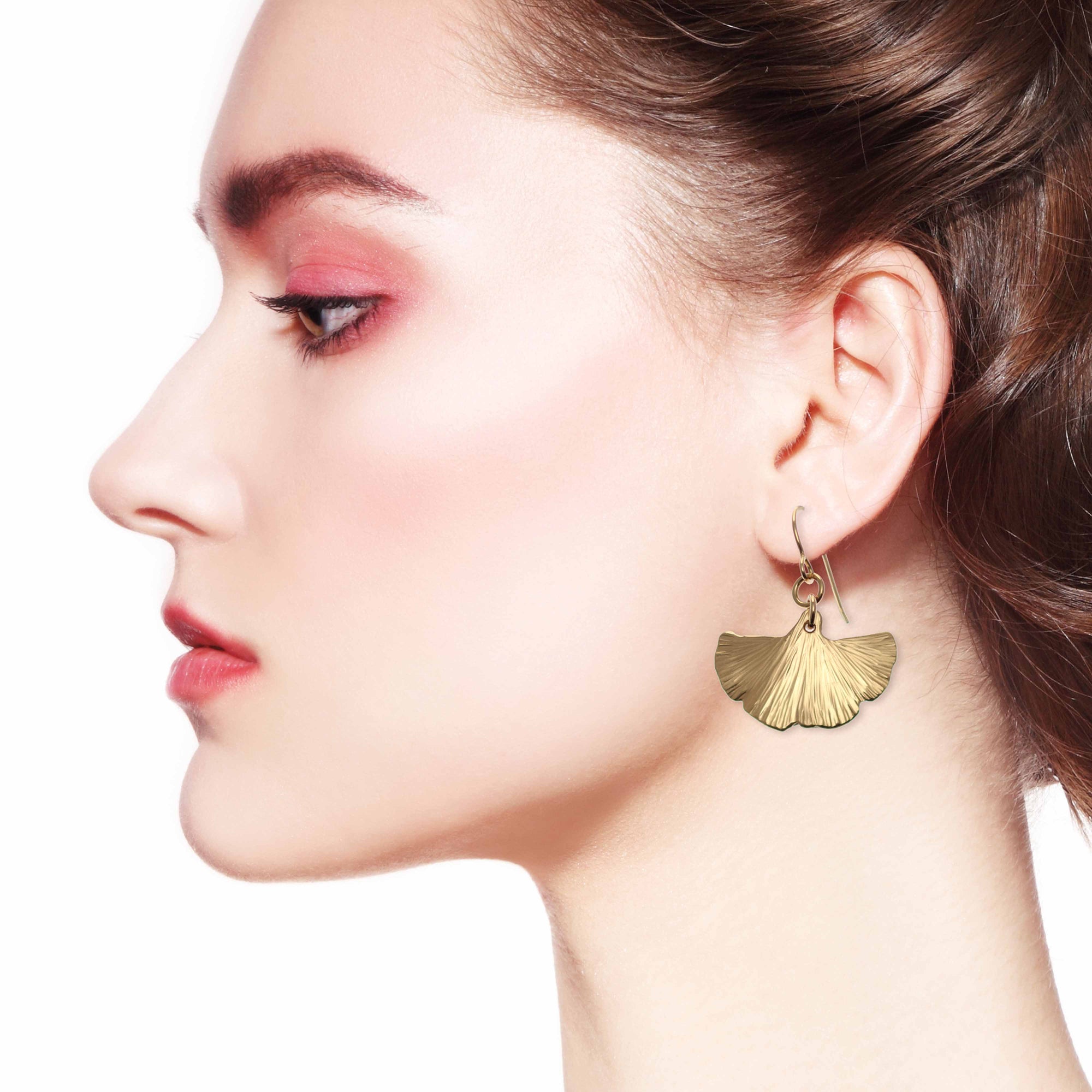 Side view of woman wearing bronze ginkgo leaf drop earrings.