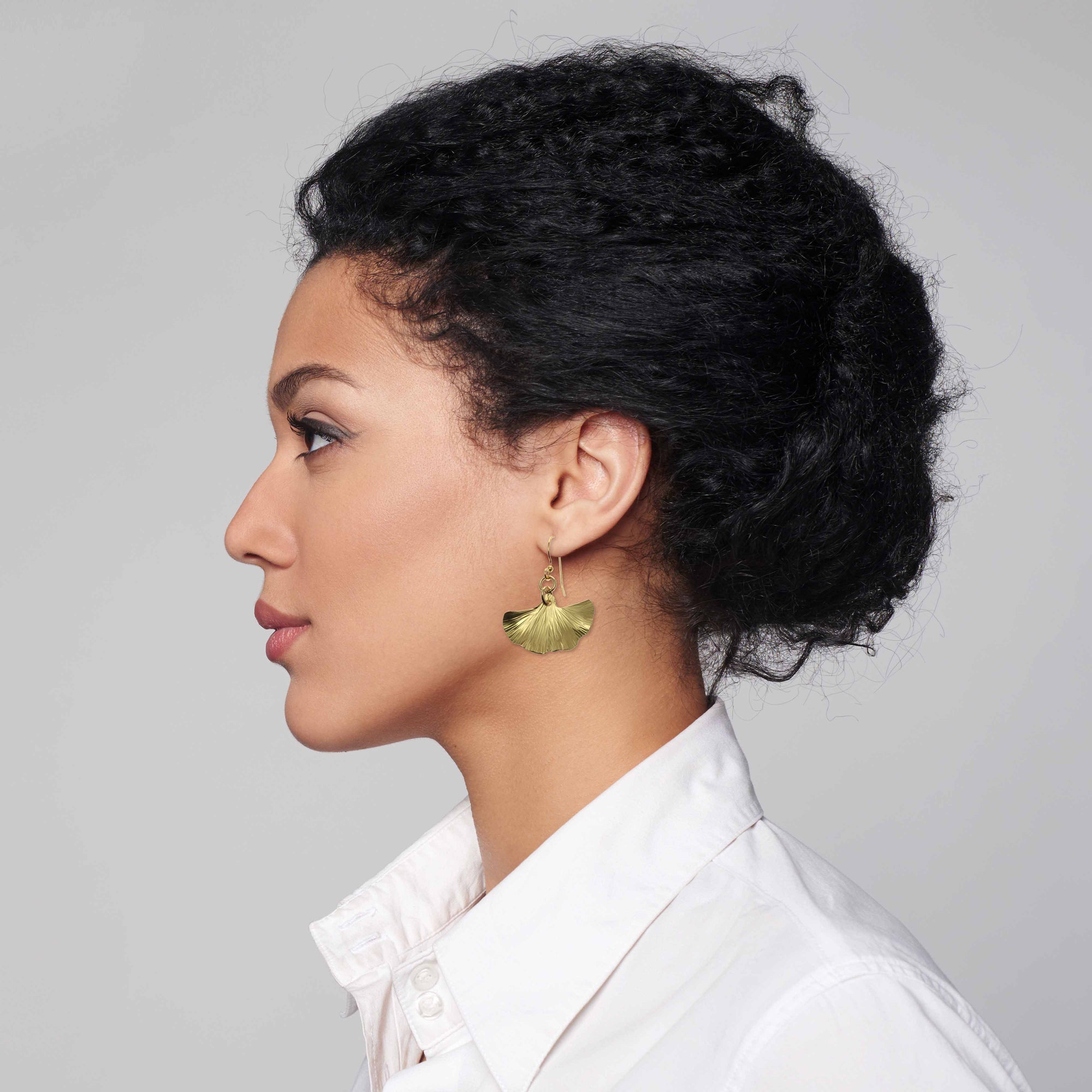 Woman in White Blouse Wearing Small Nu Gold Brass Ginkgo Leaf Earrings