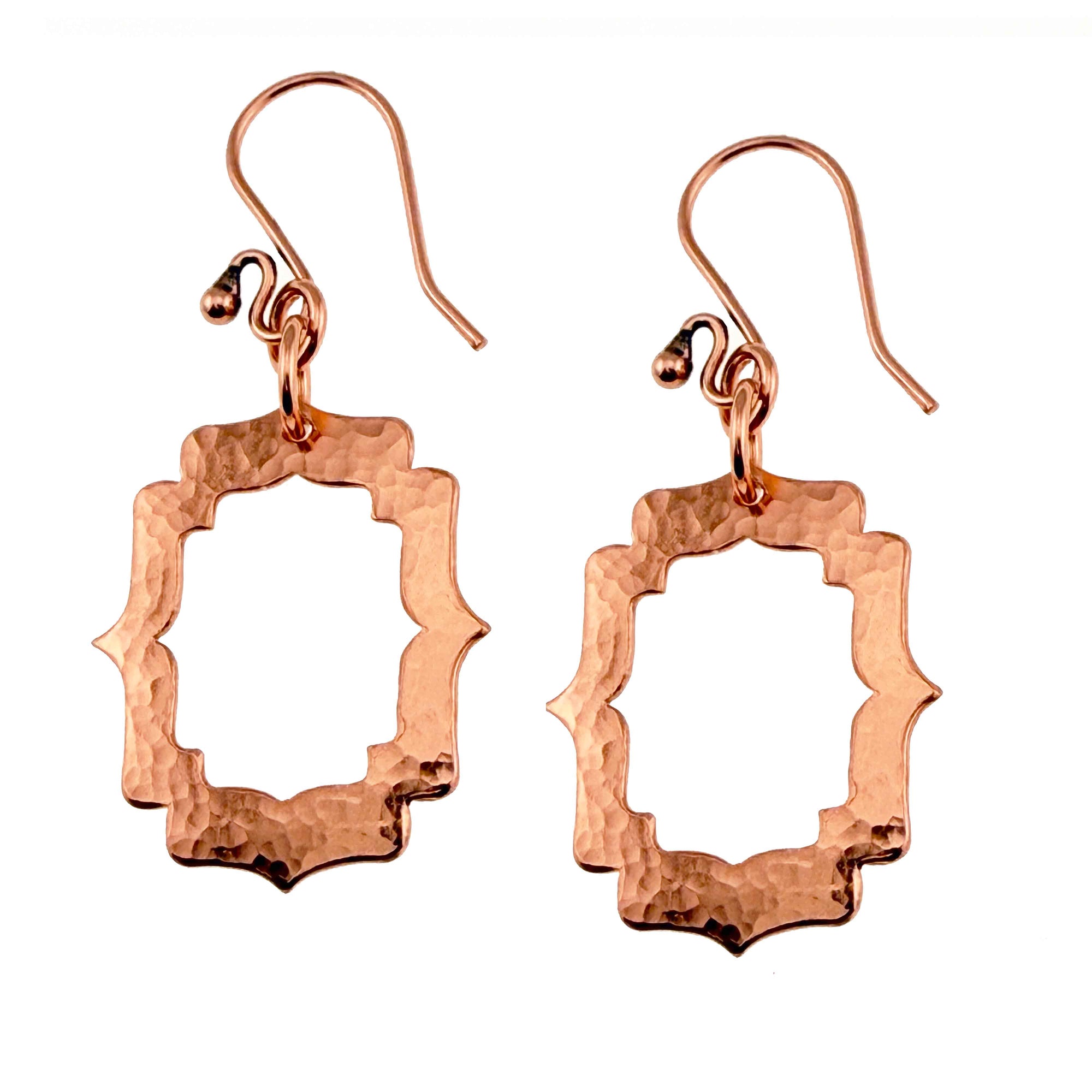 A Pair of Small Pierced Hammered Copper Arabesque Shield Earrings on a White Background